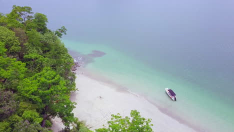 Beautiful-horizontal-to-eagle-eye-drone-shot-of-a-small-boat-in-still-water-with-nature-and-sea-surroundings