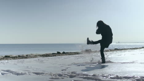 Woman-kicks-snow-in-slow-motion-on-winter-beach