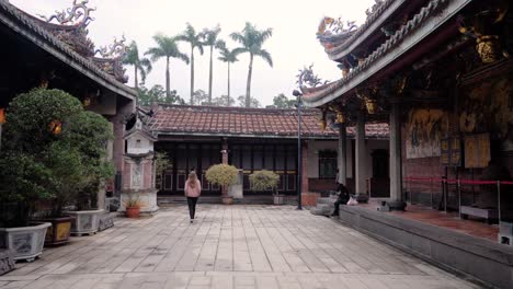 Caucasian-woman-tourist-walking-and-looking-at-Dalongdong-Baoan-Temple-in-Taipei,-Taiwan