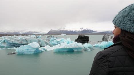 Young-Adventurous-Woman-Overlooking-Iceberg-Lake-In-Frozen-Landscape
