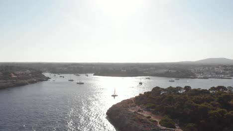 AERIAL:-Coastline-of-Mallorca-at-sunset-and-Harbor-in-bay-with-boats