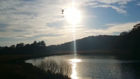 Army-National-Guard-Blackhawk-Helicopter-gets-water-with-a-Bambi-Bucket-to-fight-fires-in-the-mountains-the-helicopter-passes-through-the-sun-as-it-descends-to-get-water