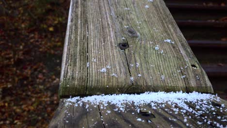 Outdoor-close-up-on-an-old-weathered-wooden-stairwell-surface-showing-first-snowfall-of-the-season