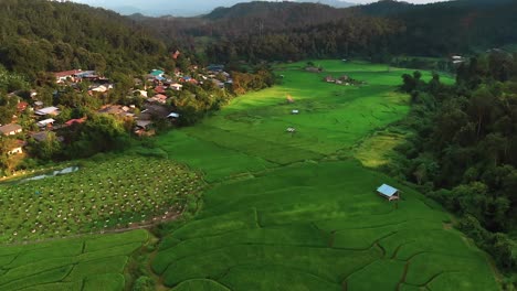 Aerial-flight-over-village-and-rice-fields-in-mountain-valley-during-sunset