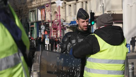 A-yellow-jacket-demonstrator-moves-towards-a-police-officer-in-full-riot-gear-to-ask-a-question