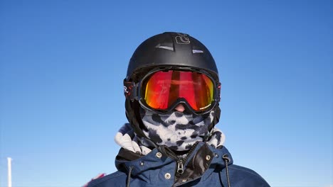 Mujer-Poniéndose-Gafas-De-Esquí-En-La-Estación-De-Esquí-Con-Cielo-Azul-En-Un-Cálido-Día-De-Nieve