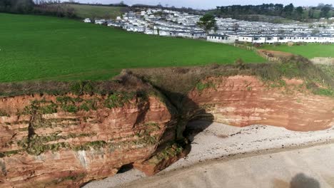 Diagonal-drone-shot-of-Jurassic-coast-cliffs-with-a-caravan-holiday-park-in-the-background