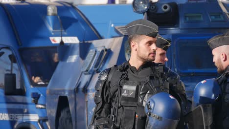 Police-officers-in-full-riot-gear-talk-in-front-of-blue-police-tanks-in-the-middle-of-the-street-before-a-demonstration-in-Marseille,-south-of-France