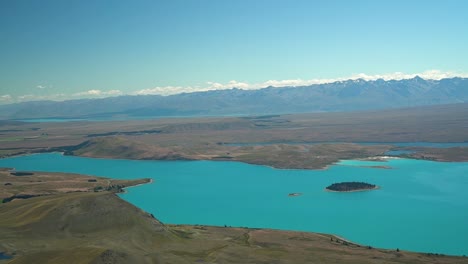 Beautiful-blue-glacier-Lake-Tekapo,-New-Zealand-from-scenic-flight-plane-with-montains-in-background