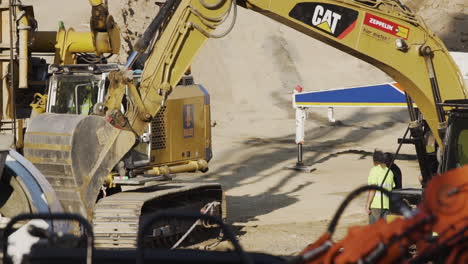 Excavator-hand-moving-around-between-a-bulldozer-and-a-truck-on-a-construction-site-in-Vienna,-Austria