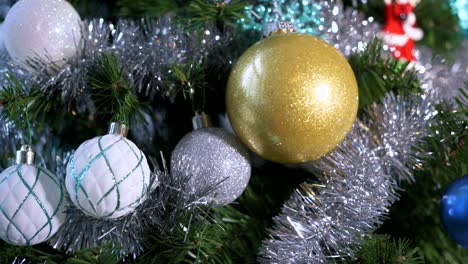 Close-up-of-decorations,-ornaments---tinsel-on-a-green-Christmas-Tree-in-a-home