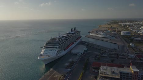 Luftaufnahme-Des-Großen-Kreuzfahrtschiffes-Im-Dock-Neben-Einem-Kleineren-Schiff-Mit-Blauem-Himmel-4k