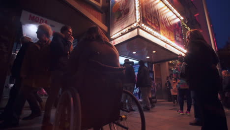 Pull-back-rotation-view-across-crowd-of-people-visiting-entertainment-show-buildings-illuminated-in-evening-light