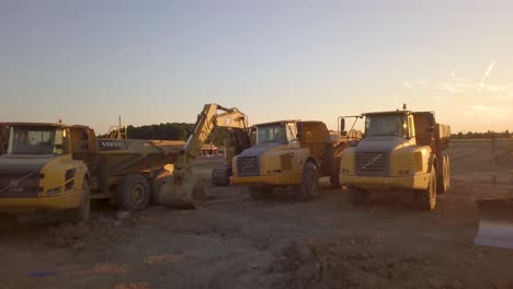 Drone-shot-fly-over-a-lot-of-heavy-machinery-parked-on-an-empty-field