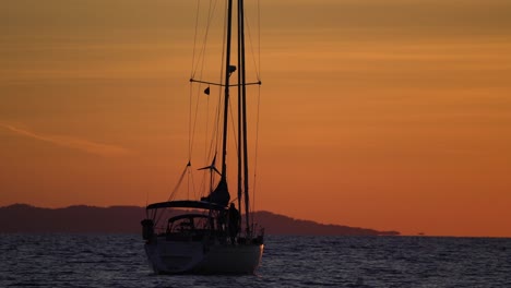 Segelboot-silhouette-Verankert-Bei-Sonnenuntergang-Mit-Mann,-Der-Fotos-Vom-Boot-Macht