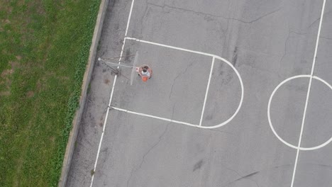 A-man-playing-basketball-on-an-empty-basketball-field-and-successfully-drop-his-basketball-into-the-basketball-ring