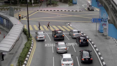 Gente-Cruzando-La-Calle-Desde-Un-Paso-De-Cebra-En-Kualalumpur