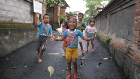 Small-group-of-Balinese-kids-jumping,-laughing-and-greeting-looking-at-the-camera-with-excitement