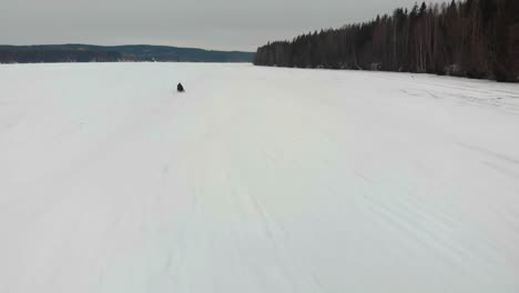 Tracking-Luftaufnahme-Eines-Mannes,-Der-Mit-Seinem-Schneemobil-Auf-Indalsalven-In-Timra,-Sundsvall,-Schweden-Fährt
