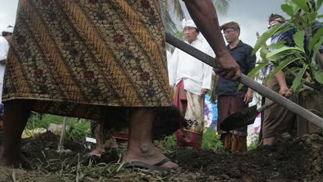 Cámara-Lenta,-Vista-De-ángulo-Bajo-De-Hombres-Balineses-Cavando-Tumbas-De-Tierra-Durante-La-Ceremonia-Fúnebre