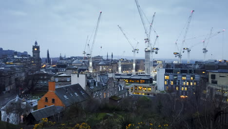 Early-morning-timelapse-of-Edinburgh-as-dawn-breaks-over-the-city,-showing-large-construction-cranes-working-and-traffic-making-its-way-through-the-streets