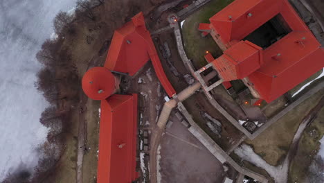 AERIAL:-Top-Shot-of-Trakai-Castle-with-Frozen-Lake-and-Trees-on-the-Ground