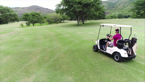 Zeitlupe-Aus-Der-Luft:-Seitenansicht-Eines-Mannes,-Der-Golfwagen-Auf-Dem-Golfplatz-Fährt