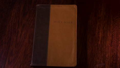 Top-down-shot-of-a-brown-leather-brown-bible-being-placed-onto-a-table-top