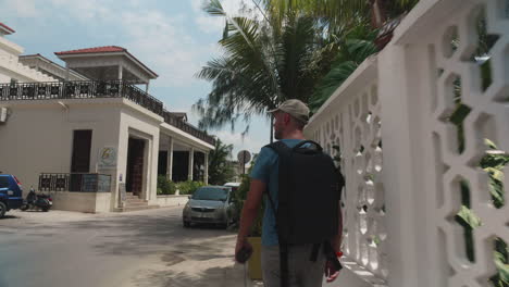 Turista-Caminando-Por-La-Calle-De-La-Ciudad-De-Piedra-De-Zanzíbar-Con-Palmeras-Y-Restaurantes-Alrededor