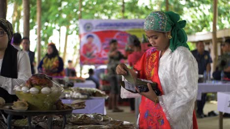 Beautiful-Filipino-woman-in-colorful-decorative-clothing-sorts-through-cards-to-be-place-on-plates-of-food-to-identify-the-dish-for-guests