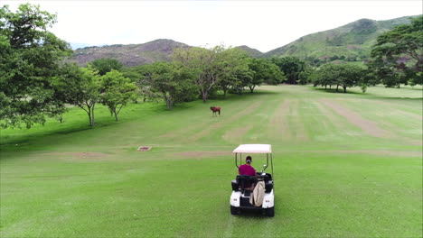 AERIAL:-Following-guy-driving-golf-cart-at-golf-course
