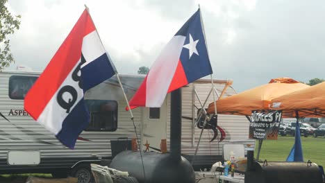 Bandera-De-Barbacoa-Y-Bandera-De-Texas-Ondeando-Frente-A-La-Caravana-Y-Los-Fumadores-De-Un-Equipo-De-Barbacoa