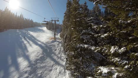 Ride-on-a-ski-lift-next-to-a-ski-track-with-trees-on-the-other-side