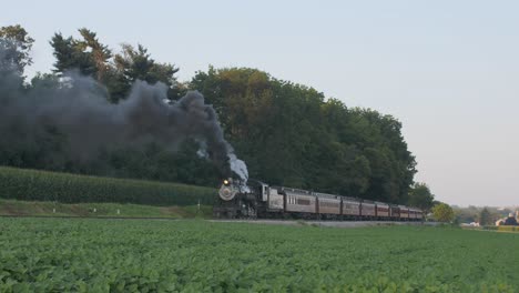 A-1924-Steam-Engine-with-Passenger-Train-Puffing-Smoke-Traveling-Along-the-Amish-Countryside-on-a-Summer-Day