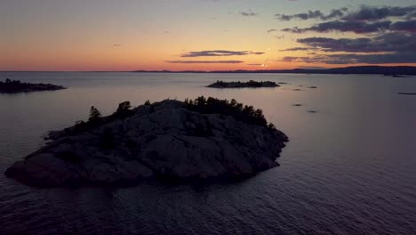 Rocky-Pine-Tree-Island-in-Big-Lake-just-after-Sunset,-Drone-Aerial-Wide-Dolly-In-Tilt-Down