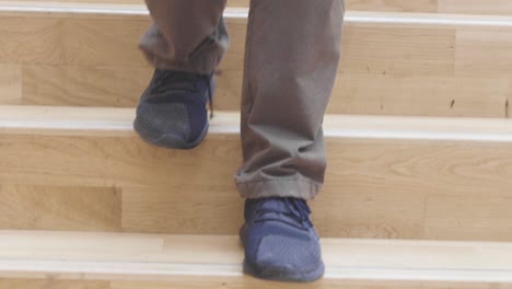 Nahaufnahme-Eines-Mannes,-Der-Mit-Dunklen-Schuhen-Und-Jeans-Eine-Breite,-Moderne-Holztreppe-Hinuntergeht