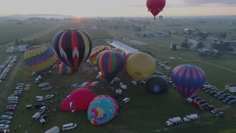 Aerial-View-of-a-Sunrise-Hot-Air-Balloons-Taking-Off-at-a-Balloon-Festival-on-a-Clear-Summer-Morning