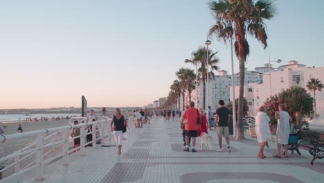 Die-Menschen-Gehen-Am-Strand-Von-Valdelagrana-In-Puerto-Santa-Maria,-Spanien,-Bei-Sonnenuntergang-Entlang
