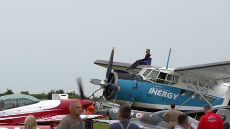 El-Piloto-Reabastece-El-Antiguo-Antonov-An-2-En-La-Exhibición-Aérea,-Sentado-En-Lo-Alto-Del-Ala-Superior-Del-Biplano-Mientras-Los-Aviones-Acrobáticos-Pasan-En-Taxi-Por-El-Avión-En-La-Exhibición-Aérea-Aerobáltica-De-Gdynia