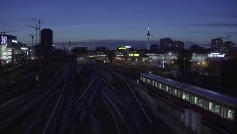 Vista-Panorámica-De-Berlín-Por-La-Noche-Con-La-Histórica-Torre-De-Televisión-Y-El-Tren-Sobre-Rieles