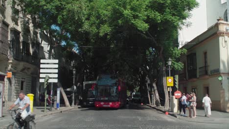 Red-double-decker-tourist-bus-pulling-up-and-stopping-in-Jerez,-Spain