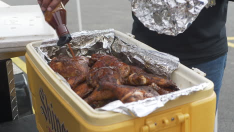 BBQ-Sauce-being-poured-on-to-a-cooler-full-of-BBQ-Chicken-Legs-and-Thighs