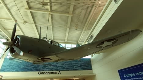 Intrépido-Bombardero-En-Picado-Cuelga-Del-Techo,-Exposición-Conmemorativa,-Avión-De-Guerra,-Decoración-De-Modelo-De-Avión-En-El-Aeropuerto-De-Chicago,-Vestíbulo-De-Conexión,-Estados-Unidos,-Historia-De-La-Aviación,-Arte-Mural-Del-Aeropuerto