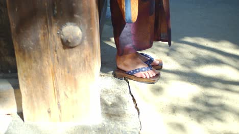 Guy-wearing-a-Yukata-leaning-against-a-wooden-wall-in-Kyoto,-Japan-soft-lighting-slow-motion-4K