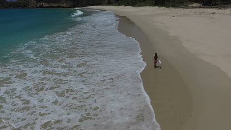 Female-in-Bikini-Running-on-Sandy-Beach-by-Sea,-Tracking-Aerial