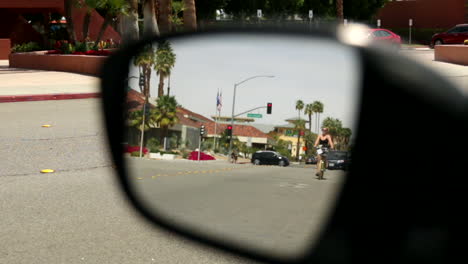 Ver-En-Un-Espejo-Retrovisor-De-Un-Automóvil-Estacionado-En-Una-Calle-Con-Tráfico-En-El-Centro-De-Palm-Springs,-California