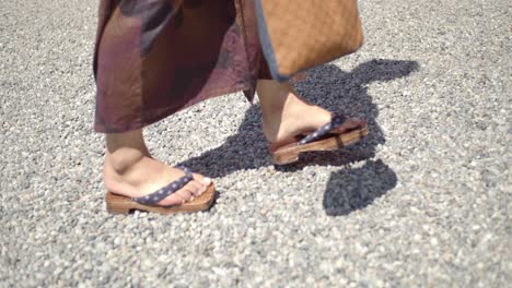 Side-angle-of-a-guy-wearing-a-yukata-wearing-traditional-wooden-sandles-walking-towards-a-temple-in-Kyoto,-Japan-soft-lighting-slow-motion-4K