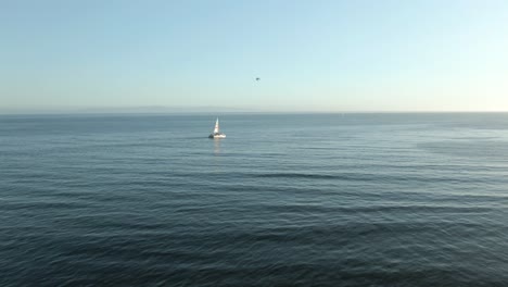 Aerial-of-tourist-sailboat-on-the-Pacific-ocean-during-sunset,-near-the-coast-of-Santa-Barbara,-California
