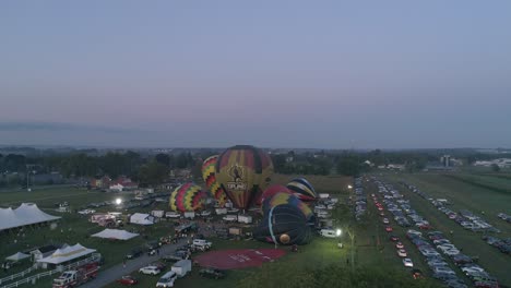 Luftaufnahme-Von-Heißluftballons,-Die-Sich-An-Einem-Sommermorgen-Bei-Einem-Heißluftballonfestival-Füllen-Und-Abheben