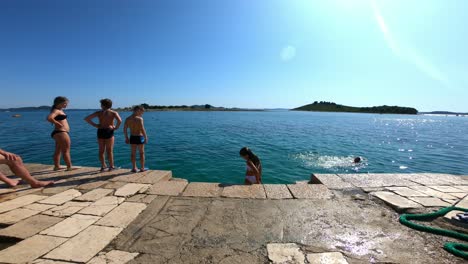 Kids-jumping-and-playing-in-sea-in-Pakostane,-Croatia